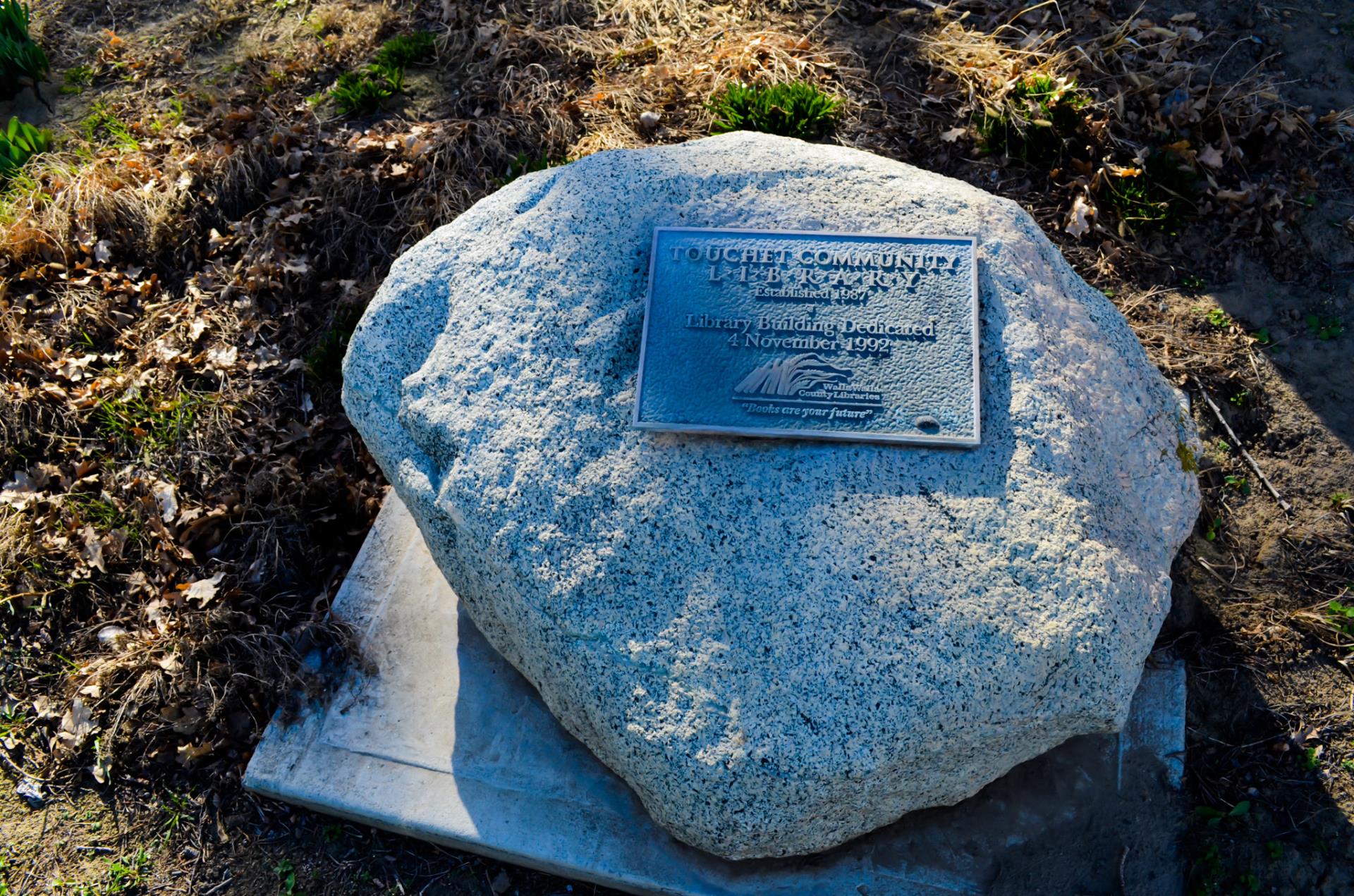 A boulder with a metal plaque reading "Touchet Library Dedicated 1992"