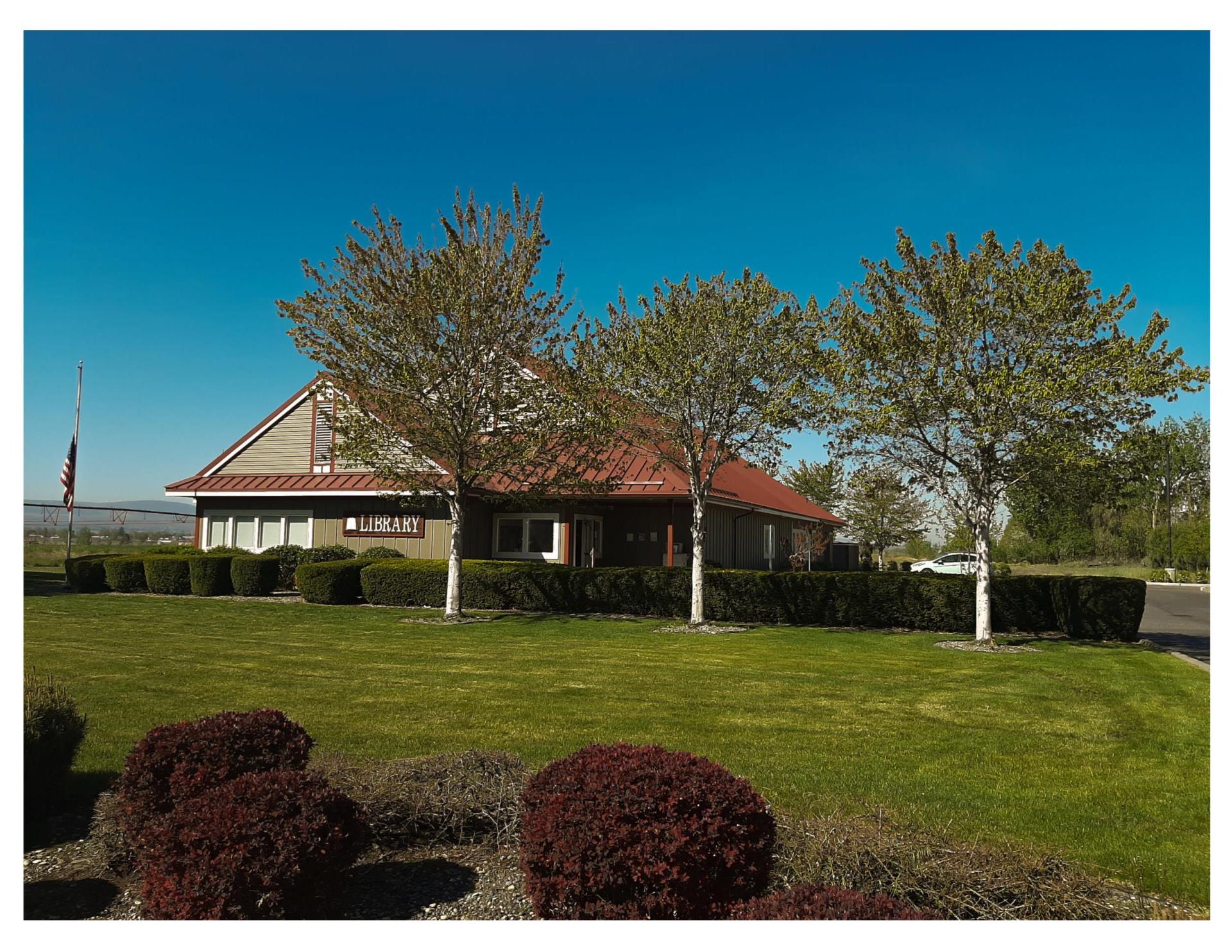 The Burbank Branch building with green trees, green grass, and a bright blue sky